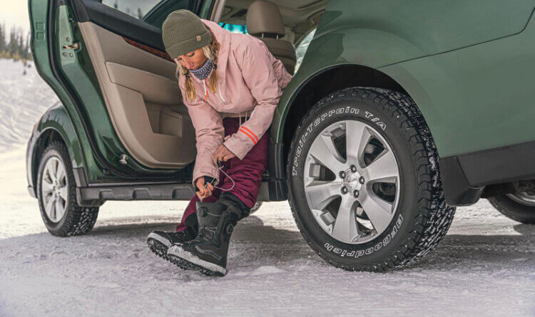 A women putting on boots in the snow sat in the back of her 4x4 using a BFGoodrich Trail Terrain tyre
