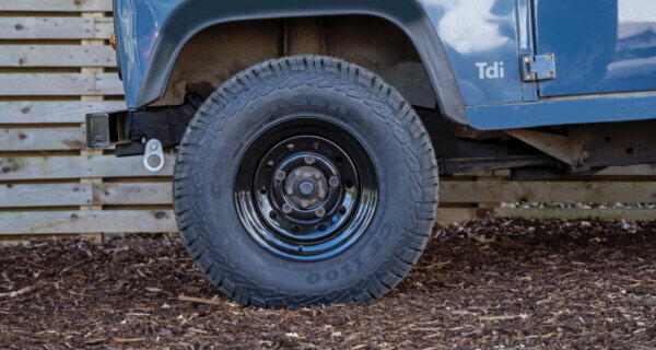 a blue vintage land rover shown on wood chips