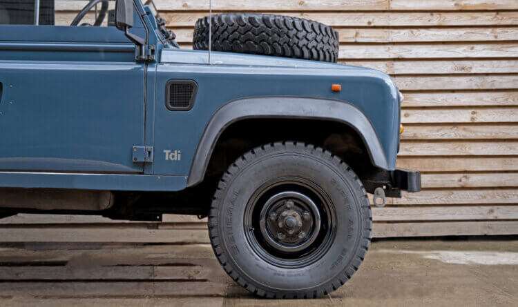 Vintage land rover showing a wheel and tyre package shot in front of a wood wall