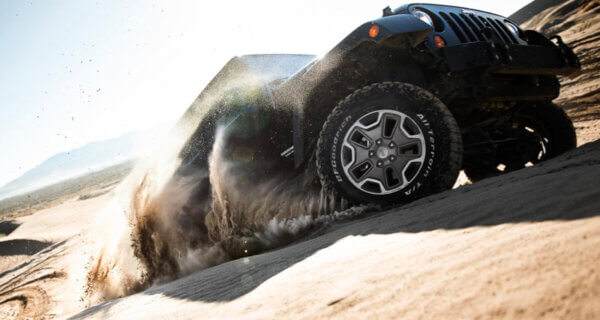 A jeep driving up a sandy hill on a bfgoodrich at k02 tyre showing off its Superior Traction