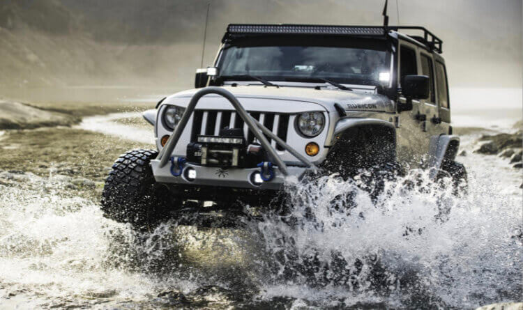 A jeep drive through water making a big splash sat on KM3 BFGoodrich Mud Terrain tyres