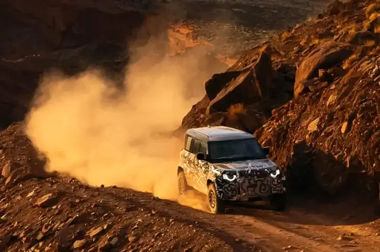 Defender Octa driving along a dusty mountain range to show its built to Conquer