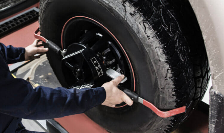 Wheel and tyre alignment happening in a garage to illustrate tyre safety wheel Alignment and tyre care