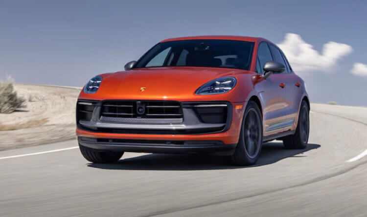 The new electric porsche macan in burnt orange driving along a costal road is a Sustainable Porsche