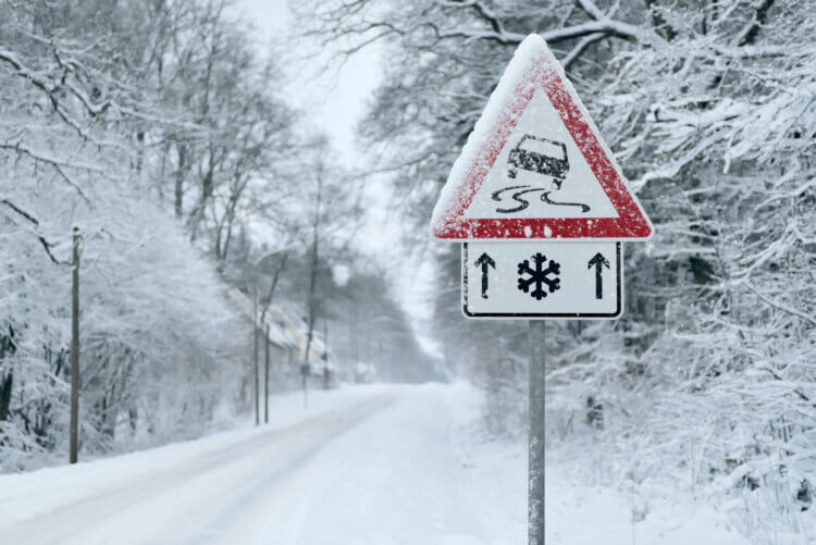 A snowy road and road sign for winter driving