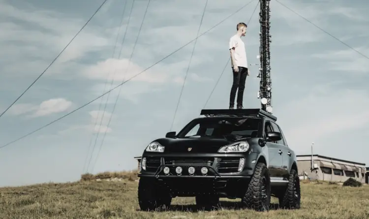 Overlanding Porsche with alex stood on top of his vehicle