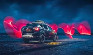 A Ford Kuga on a beach with epic neon lights around. It shows its overlanding ability