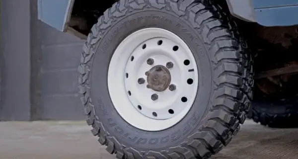 A classic white steel wheel on a vintage landrover