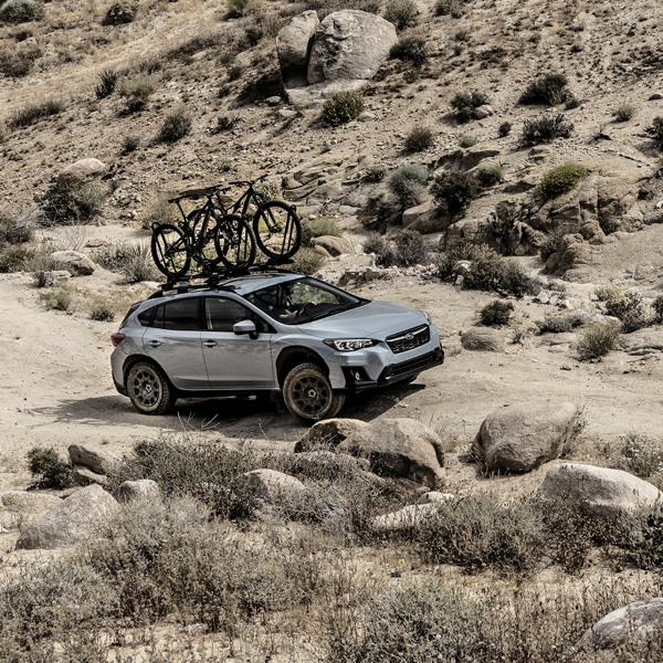 Subaru SUV with bicycles on the roof driving on a rocky off-road trail