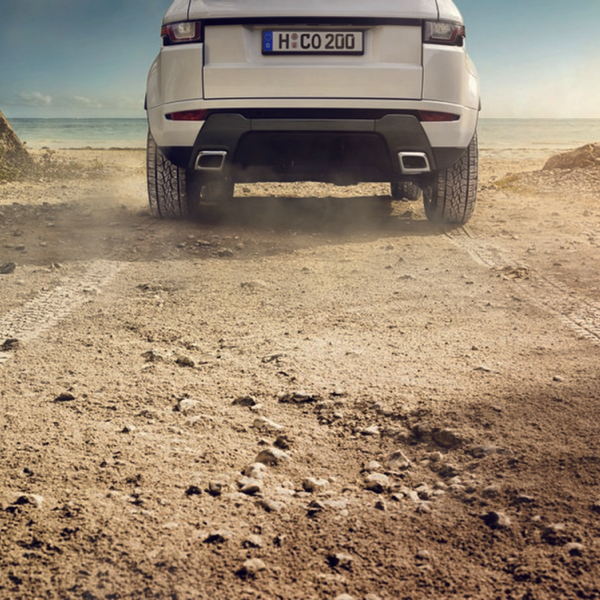 Rear view of an SUV driving on a dusty off-road track