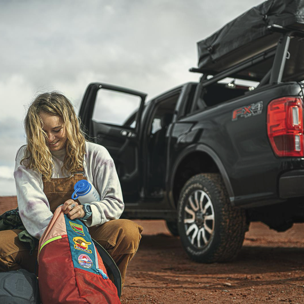 Woman preparing camping gear beside a Ford pickup fitted with BFGoodrich Trail-Terrain T/A tyres
