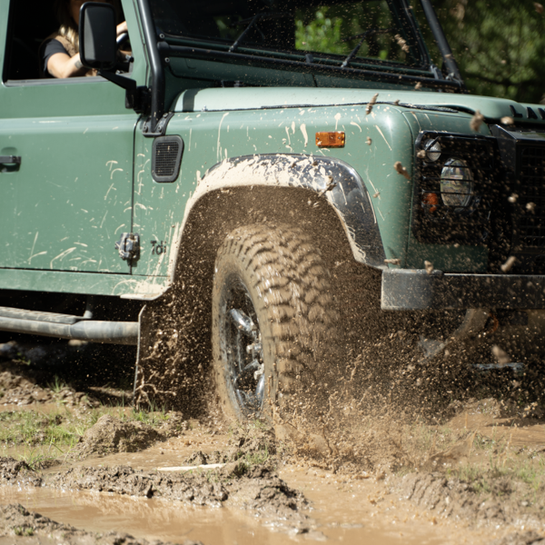 Land Rover Defender driving through deep mud on Comforser mud-terrain tyres